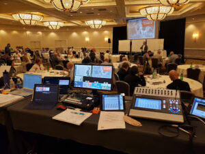Conference event with AV control station, mixing consoles, and presentation screens by Lucas Productions USA