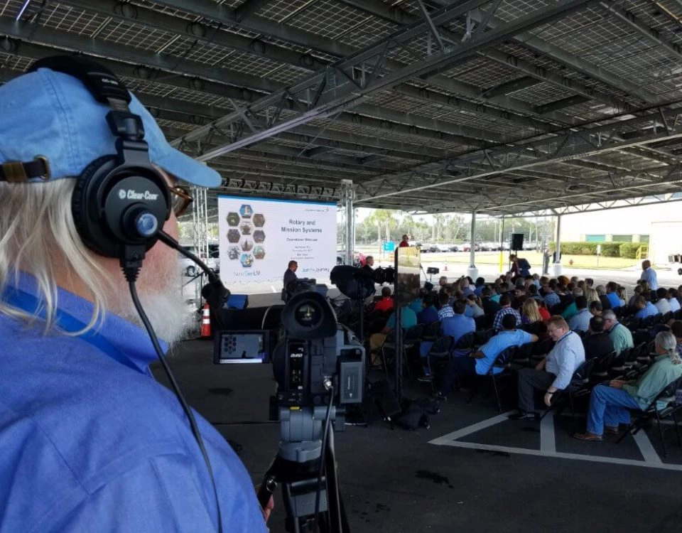 Outdoor corporate event with audience seating and AV crew managing live video production by Lucas Productions USA