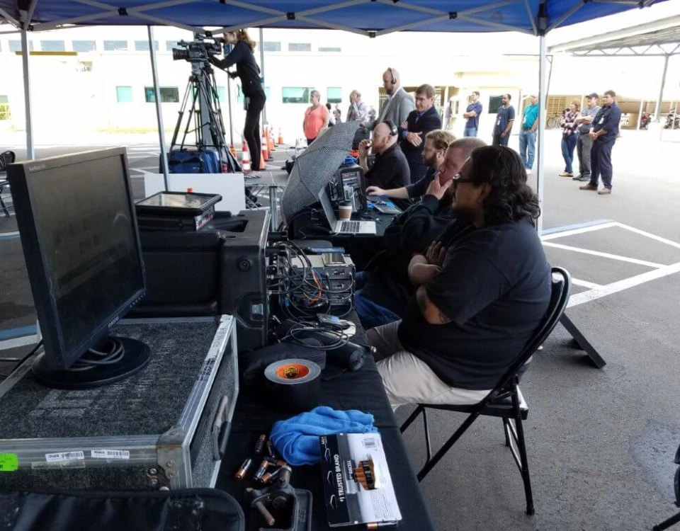 Outdoor AV production team operating mixing consoles and video equipment for live event by Lucas Productions USA