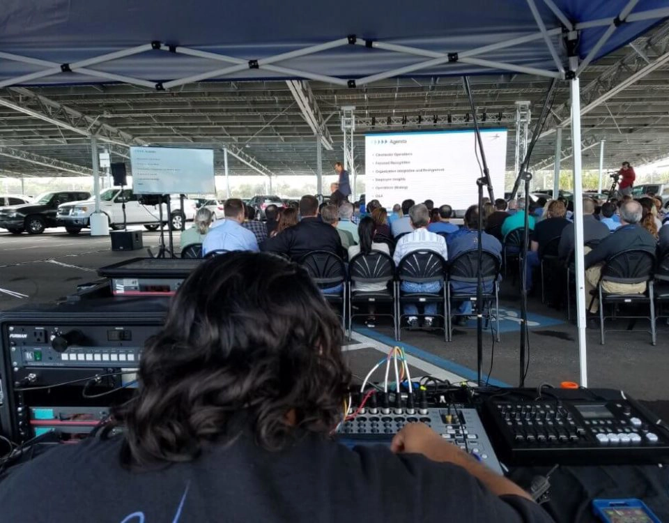 Event production specialist operating sound and AV equipment at outdoor conference