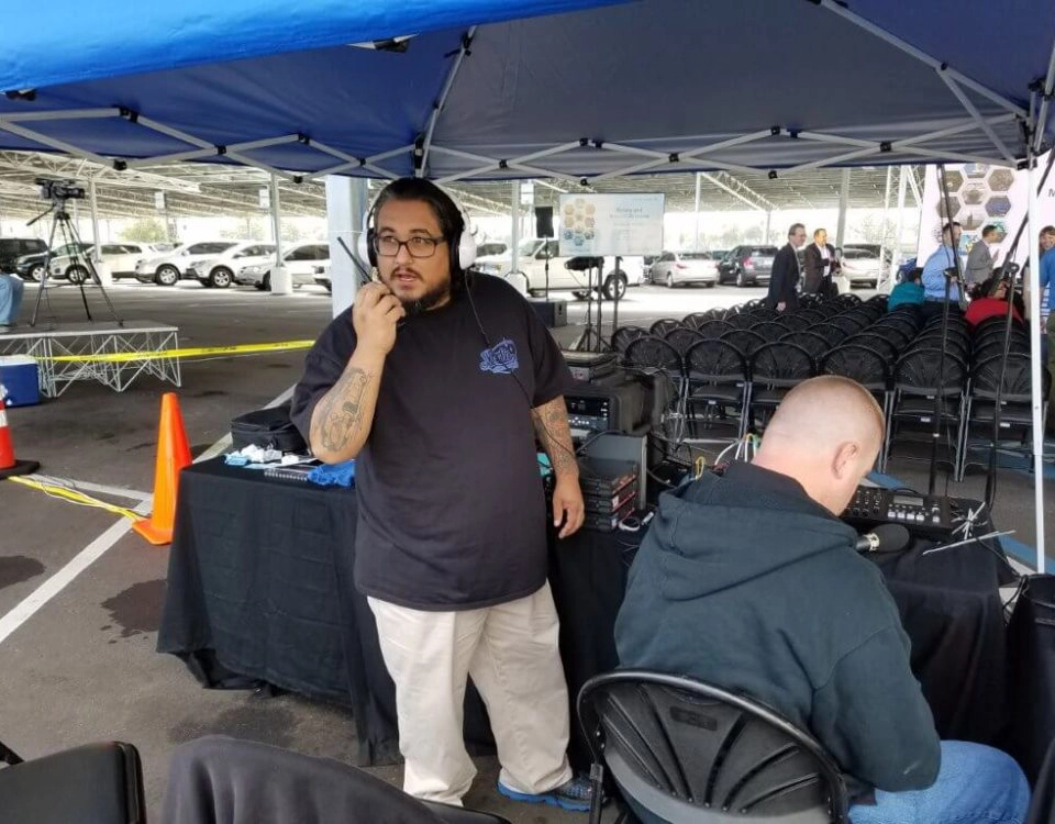Event technician managing outdoor AV production with headset and control systems