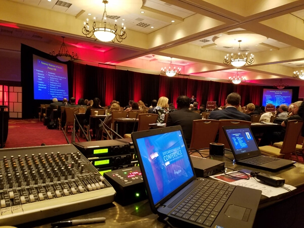 Corporate conference AV production with laptops, soundboard, and live event management.