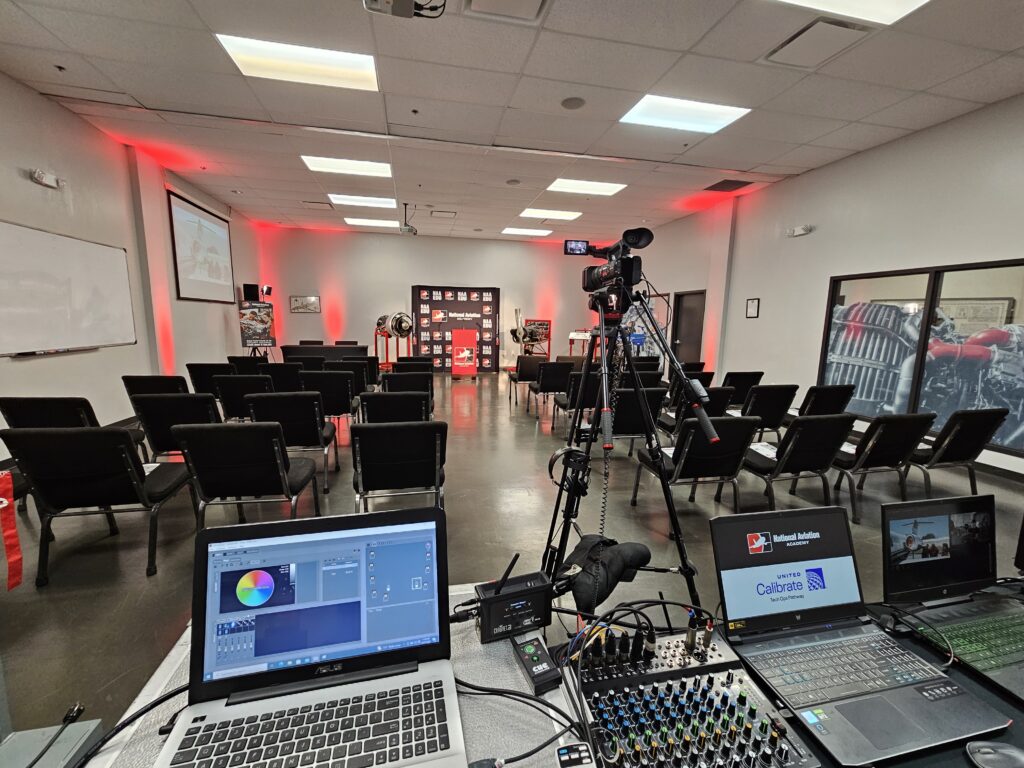 professional AV control setup with laptops, mixing consoles, and video equipment at a corporate event